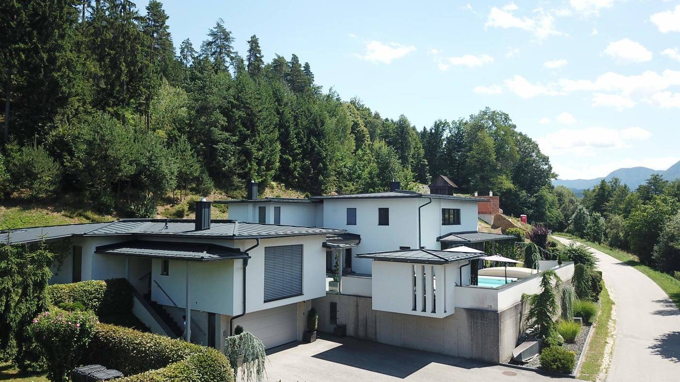 Großzügiges modernes Haus in Hanglage, umgeben von Wald und mit Blick auf die Landschaft.