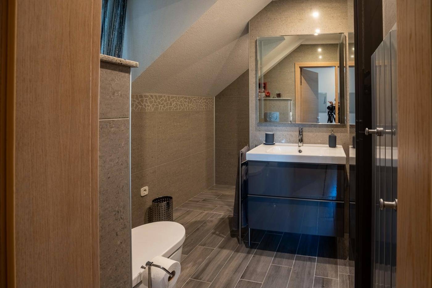 Kleines Badezimmer im Dachgeschoss mit modernen Fliesen, Waschtisch und Wand-WC.