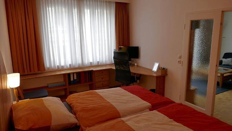 Schlafzimmer mit Doppelbett, Schreibtisch am Fenster und Blick nach draußen.