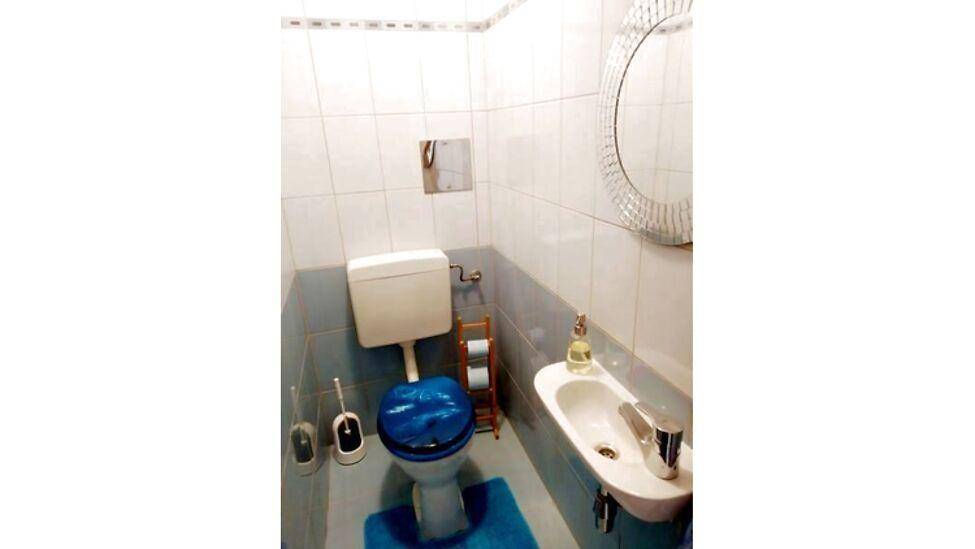 Kleines Gäste-WC mit Toilette, Handwaschbecken und einem dekorativen Spiegel.