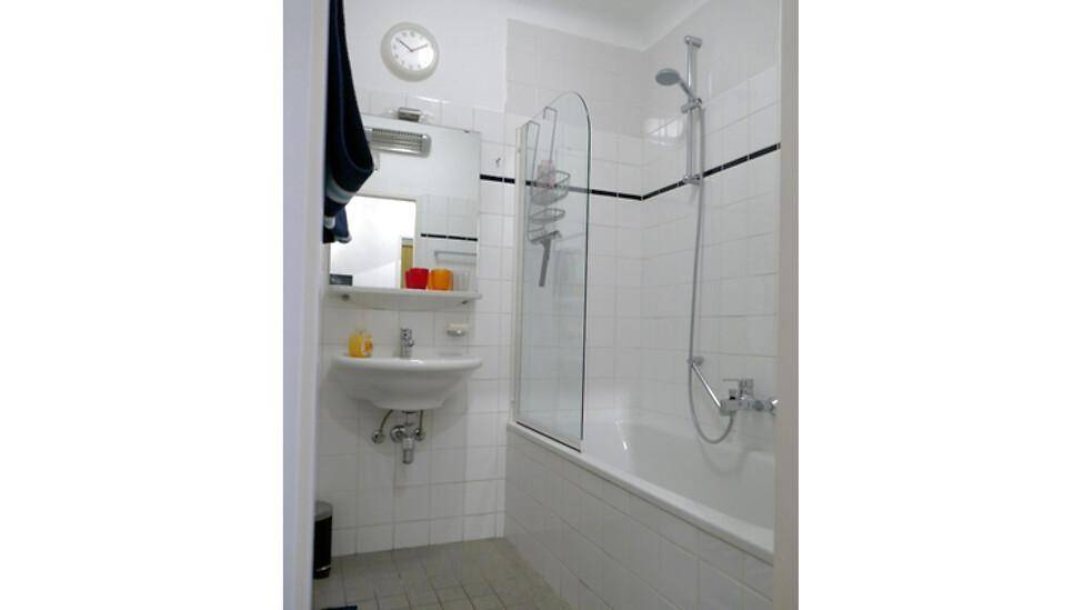 Helles Badezimmer mit Badewanne, Duschfunktion, Waschbecken und weißen Fliesen.
