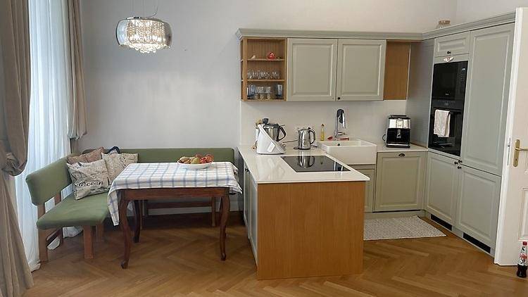 Moderne Einbauküche mit Kochinsel, integrierten Geräten und Essbereich mit Sitzbank.