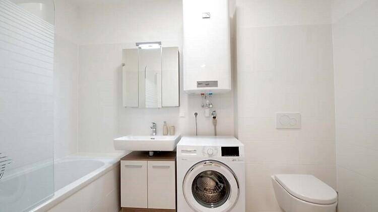 Modernes Badezimmer in Weiß mit Badewanne, Waschmaschine und wandhängendem WC.