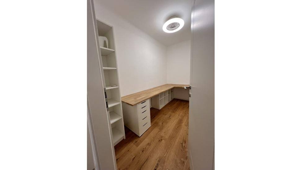 Funktionales Arbeitszimmer mit großem Eckschreibtisch, Regalen und Holzboden.