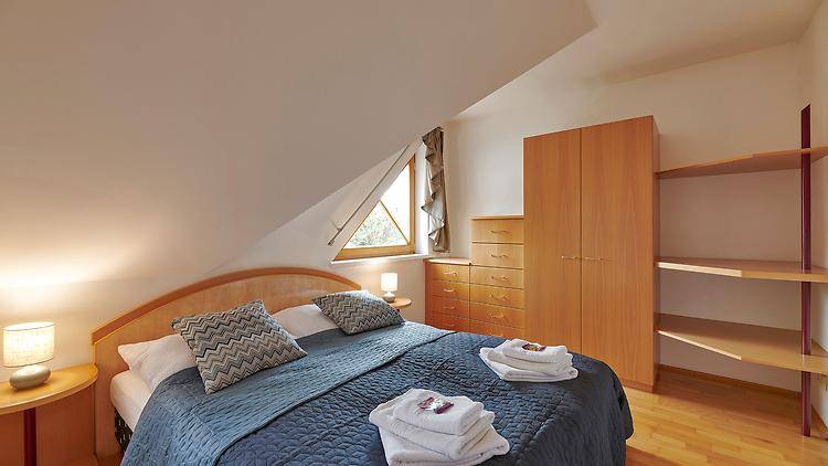 Schlafzimmer im Dachgeschoss mit Doppelbett, Holzmöbeln und schräger Decke.