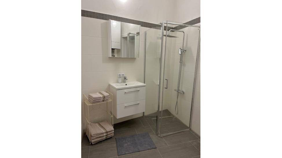 Modernes Badezimmer mit Duschkabine, Waschbeckenunterschrank und Spiegelschrank.