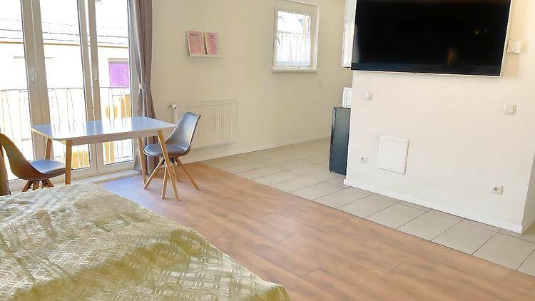 Geräumiges Schlafzimmer mit Laminatboden, Fliesenbereich und Blick auf den Außenbereich.