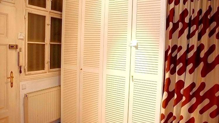Weiße Lamellenschränke neben einem Fenster und einem gemusterten Vorhang.