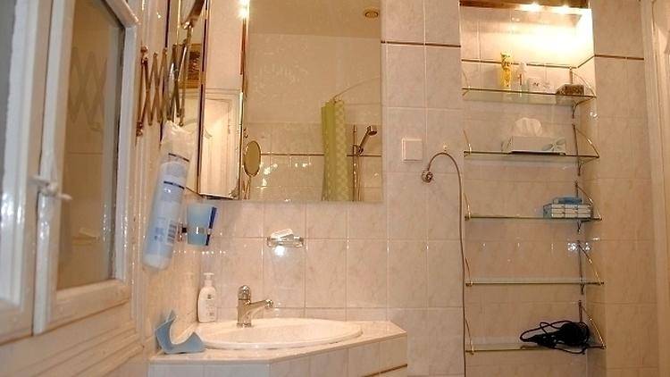 Badezimmer mit Waschbecken, Spiegelschrank, Glasregalen und Fenster.