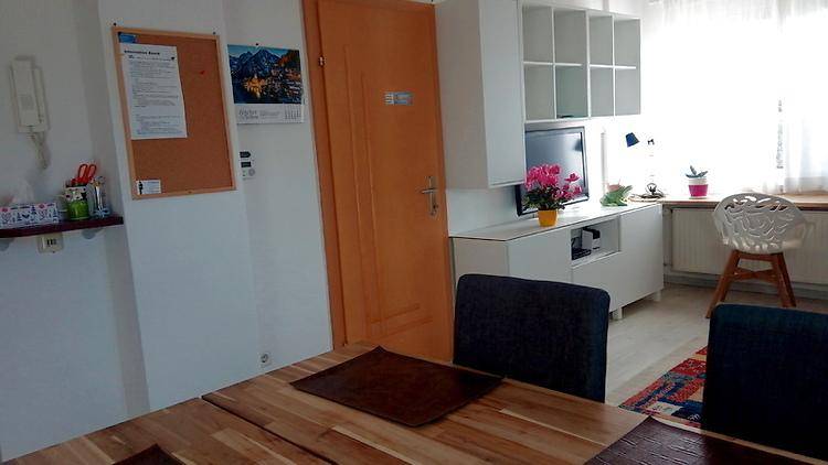 Wohn- und Essbereich mit Holztisch, TV-Möbeln und Regalen, hell und funktional eingerichtet.