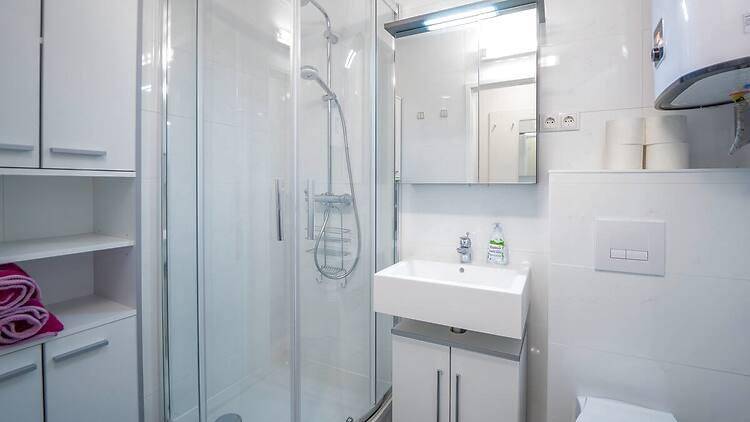 Modernes Badezimmer mit Duschkabine, Waschbecken und weißen Fliesen.