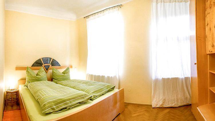 Helles Schlafzimmer mit zwei Einzelbetten, Holzboden und großen Fenstern für viel Tageslicht.