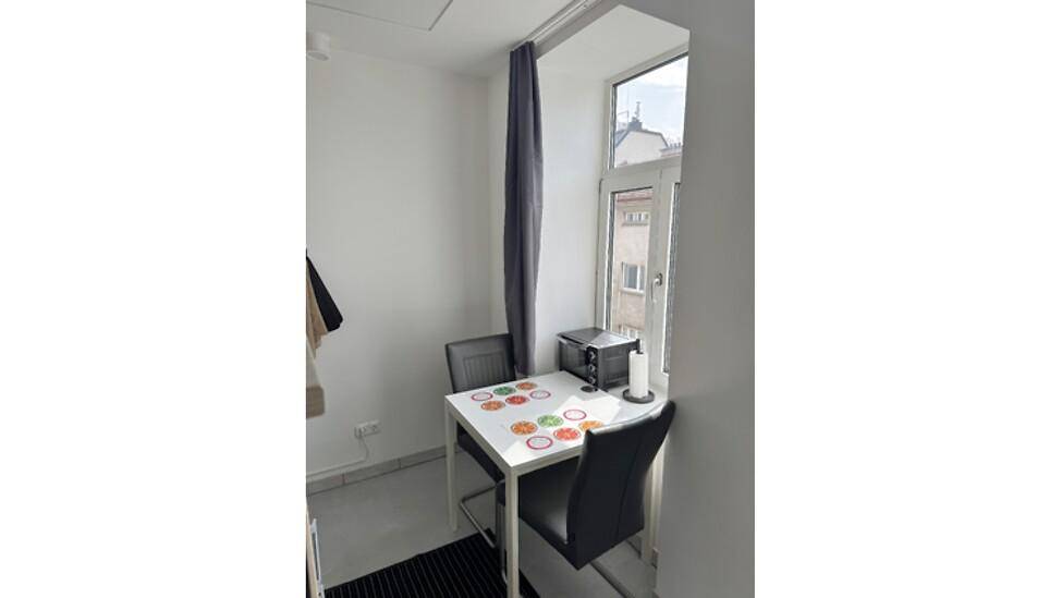 Kleiner Essbereich mit Tisch und Stühlen neben einem Fenster für Tageslicht.
