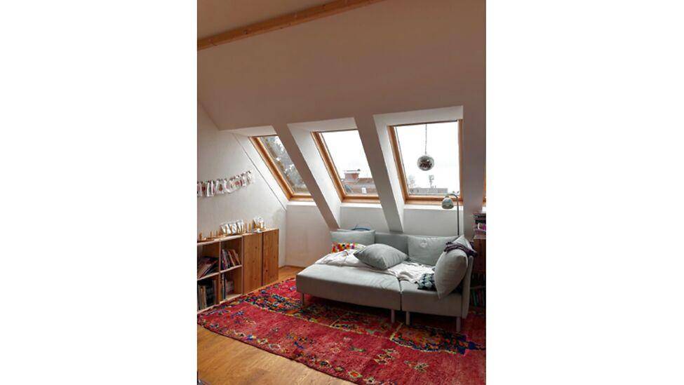 Helles Schlafzimmer im Dachgeschoss mit mehreren Dachfenstern, Holzboden und einem bequemen Sofa.