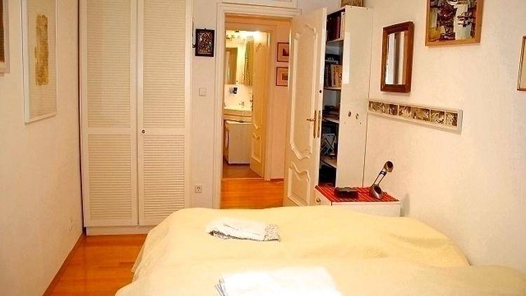 Schlafzimmer mit Doppelbett, weißen Einbauschränken und Zugang zu einem Badezimmer.