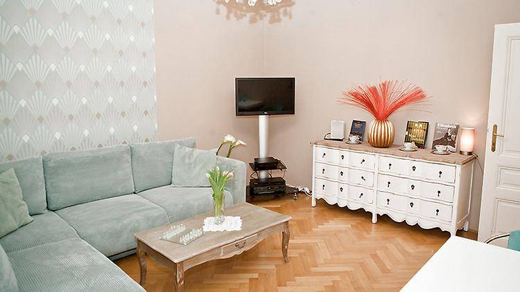 Gemütliches Wohnzimmer mit Ecksofa, Kommode und Fernseher an der Wand für Unterhaltung.