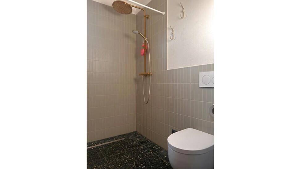 Modernes Badezimmer mit begehbarer Dusche, grauen Fliesen und wandhängendem WC.