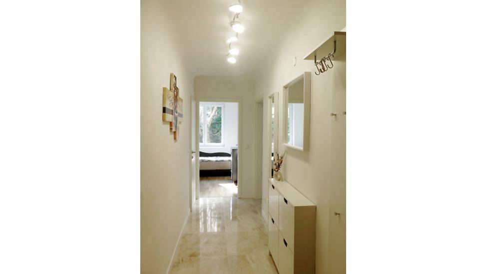 Heller Flur mit Marmorboden, Garderobe und Blick in ein angrenzendes Schlafzimmer.