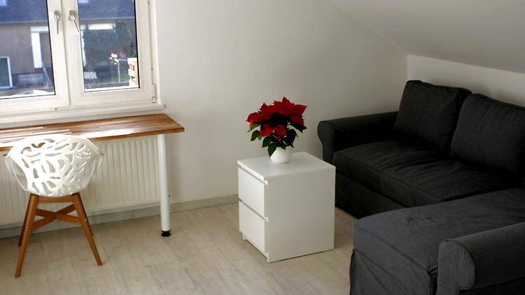 Gemütliche Sitzecke mit dunklem Sofa, Beistelltisch und Fenster mit Blick nach draußen.