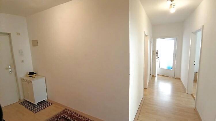 Heller Flur mit Holzboden und Zugang zu verschiedenen Zimmern der Wohnung.