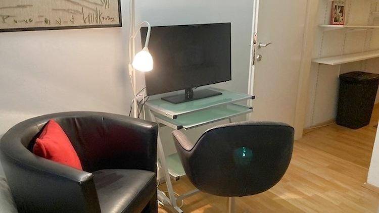 Arbeitsbereich im Schlafzimmer mit Fernseher, Schreibtisch und bequemen Stühlen.