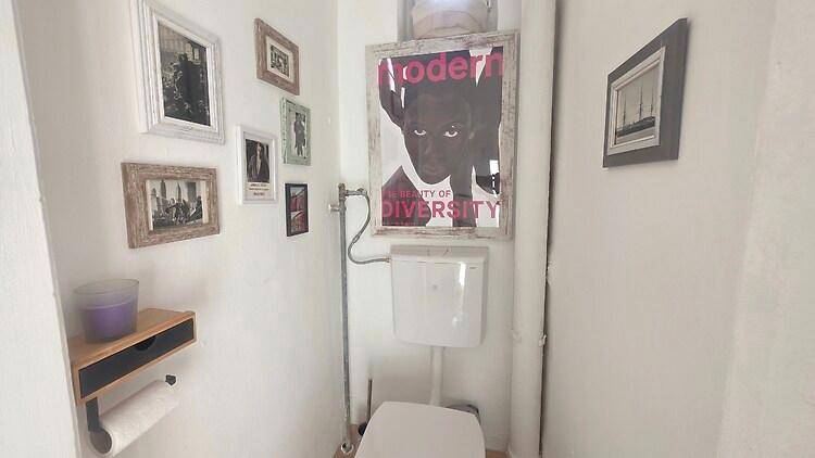 Kleines Gäste-WC mit Toilette, Waschbecken und dekorativen Bildern an der Wand.