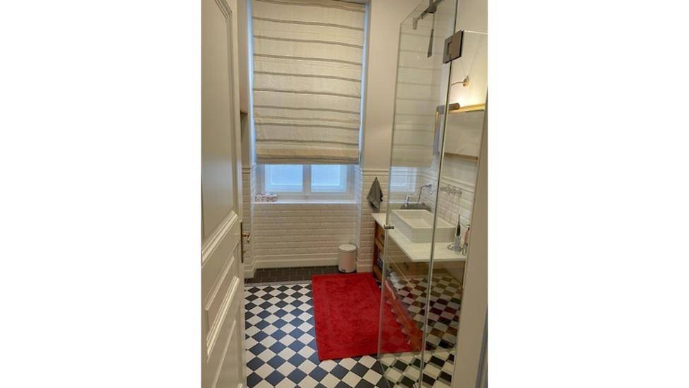 Modernes Badezimmer mit Duschkabine, Fenster und schwarz-weißem Fliesenboden.