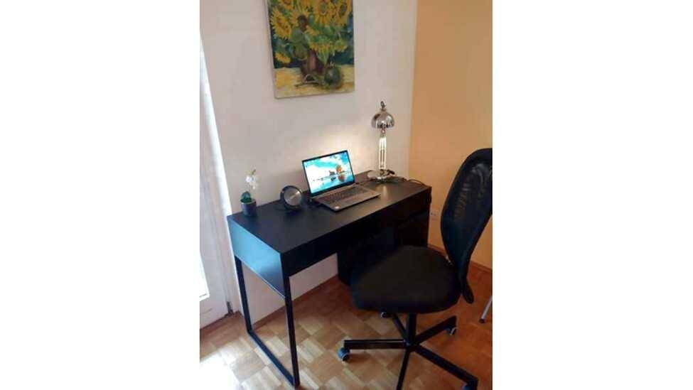 Heller Arbeitsbereich mit Schreibtisch, Laptop und Bürostuhl, ideal für Home-Office.