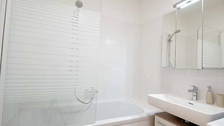 Helles Badezimmer mit Badewanne, Duschabtrennung und modernem Waschbecken.