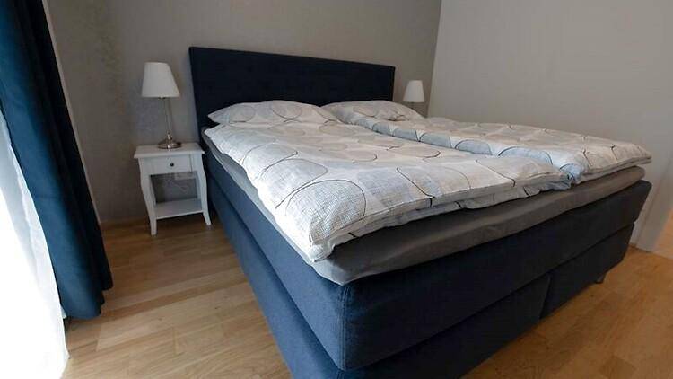 Gemütliches Schlafzimmer mit Doppelbett, Holzboden und Nachttischen.