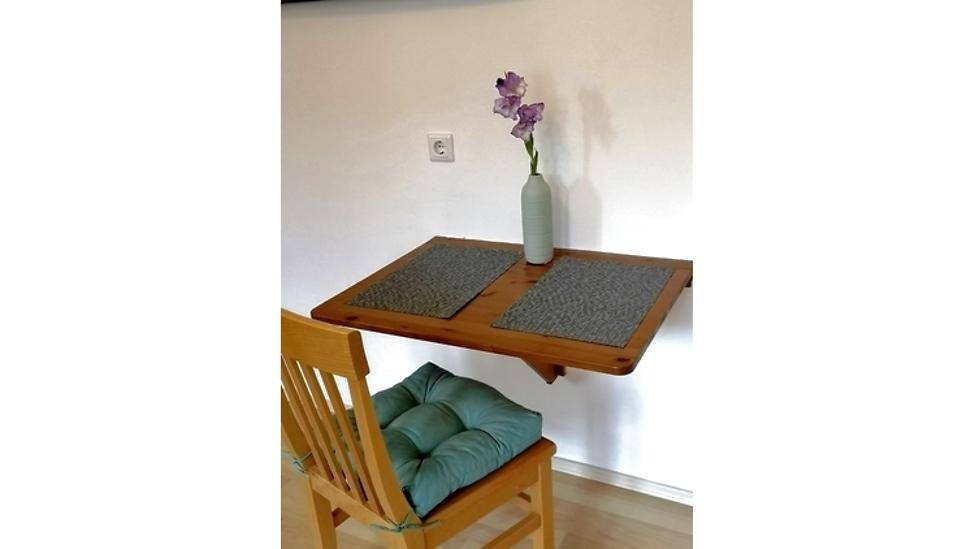 Kleiner Essbereich mit Klapptisch und Holzstuhl an der Wand.