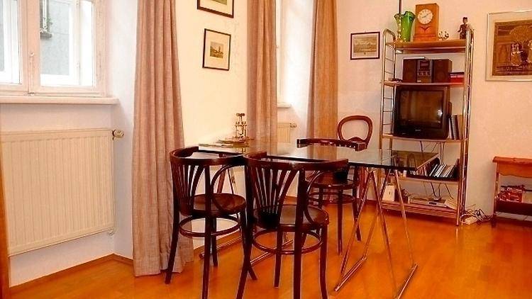 Essbereich mit Glastisch, Holzstühlen und einem Regal neben dem Fenster.