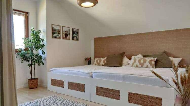 Gemütliches Schlafzimmer mit Dachschräge, Doppelbett und Fenster, das viel natürliches Licht bietet.