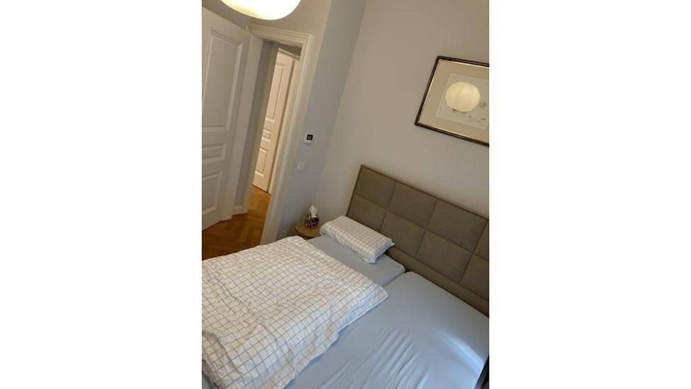 Gemütliches Schlafzimmer mit Doppelbett, Holzboden und Zugang zu einem weiteren Raum.