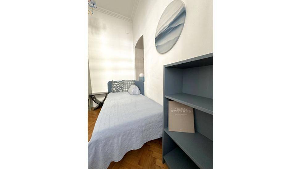 Helles Schlafzimmer mit Einzelbett, Regal und minimalistischer Einrichtung, ideal für Gäste.