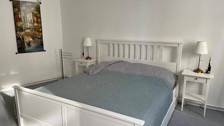 Gemütliches Schlafzimmer mit weißem Doppelbett, Nachttischen und passenden Lampen.
