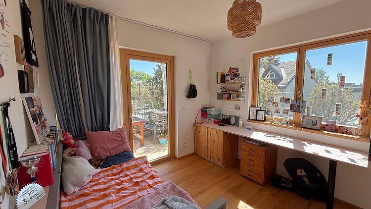Helles Schlafzimmer mit Holzboden, großem Fenster und Zugang zu einem Außenbereich.