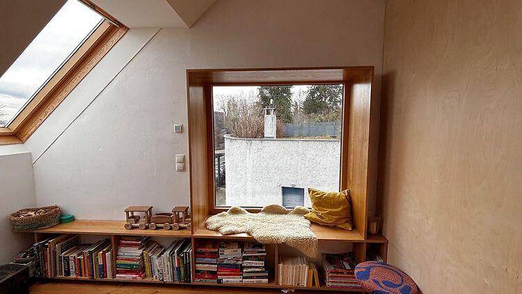 Gemütliche Leseecke im Dachgeschoss mit Dachfenstern, Holzelementen und integriertem Bücherregal.