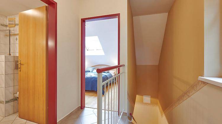 Flur im Obergeschoss mit Zugang zu Schlafzimmer und Badezimmer, hell gefliest.