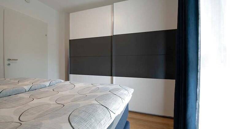 Schlafzimmer mit großem Kleiderschrank in Weiß und Grau sowie Holzboden.