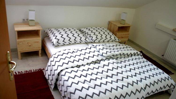 Schlafzimmer mit Doppelbett, zwei Nachttischen und modern gemusterter Bettwäsche.