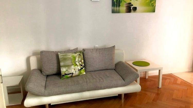 Nahaufnahme eines modernen Sofas im Wohnzimmer mit Parkettboden und minimalistischer Dekoration.