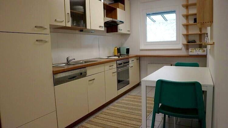 Funktionale Küche mit hellen Einbauschränken, Esstisch und Fenster für natürliches Licht.