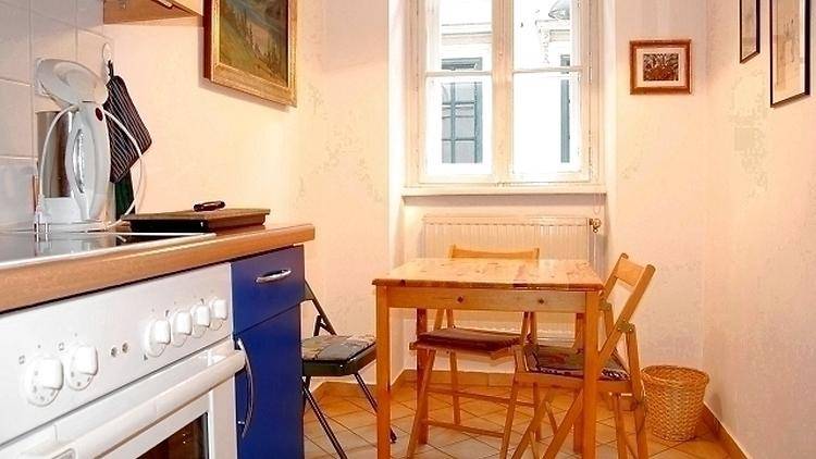Küchenbereich mit kleinem Esstisch, Stühlen und einem Fenster für natürliches Licht.