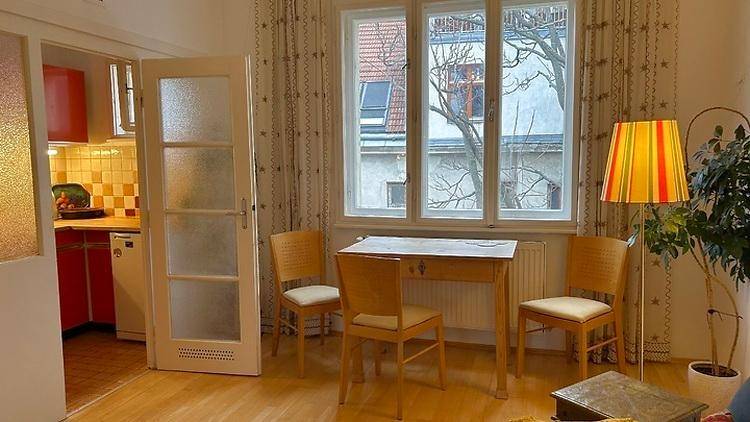 Heller Essbereich im Wohnzimmer mit Blick auf die Küche und Fenster mit Vorhängen.