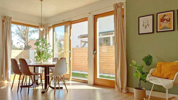 Heller Essbereich mit Holzboden, großen Fenstern und Zugang zum Garten, ideal für gesellige Mahlzeiten.