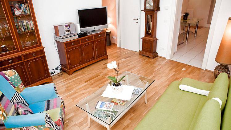 Wohnzimmer mit Holzboden, traditionellen Möbeln und einem Blick in den angrenzenden Essbereich.