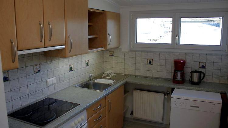 Funktionale Küche mit hellen Holzschränken, Fliesenrückwand, Spüle und Fenster.