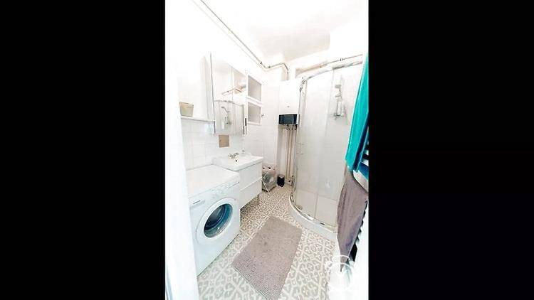 Modernes Badezimmer mit Duschkabine, Waschbecken und integrierter Waschmaschine.