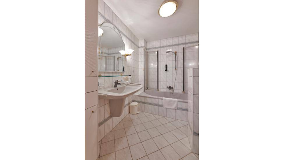 Gefliestes Badezimmer mit Badewanne, Duschabtrennung und Einzelwaschbecken.